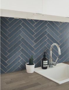 a white sink sitting under a faucet next to a blue tiled backsplash