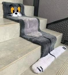 a cat rug is on the stairs next to a carpeted stair case with yellow eyes