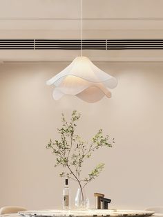 a dining room table with a vase on it and a lamp hanging from the ceiling