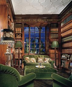 a living room filled with green couches and lots of books on the shelves next to each other