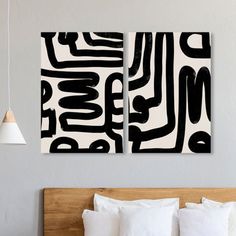 two black and white paintings on the wall above a bed