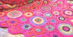 a pink crocheted blanket on top of a bed