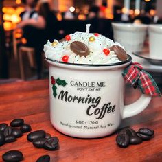 a coffee mug filled with whipped cream and toppings sitting on top of a wooden table