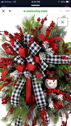 a christmas wreath with a snowman ornament and red ribbon on it's center