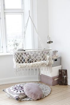 a baby crib hanging from the ceiling in a room with white walls and wooden floors