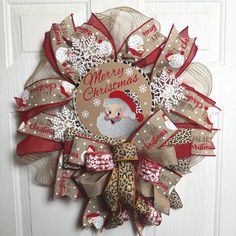 a christmas wreath with santa claus on it hanging from the front door, decorated with burlap and ribbon