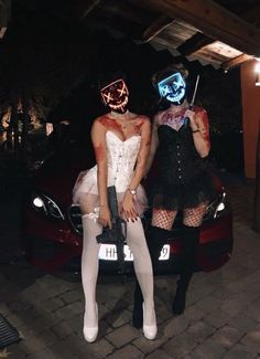 two people dressed up in costumes sitting on top of a car