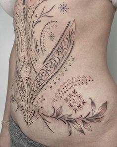 a woman's stomach with an intricate tattoo design on the side, and flowers