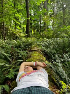 a person laying down in the woods with their arms stretched out and head resting on his chest