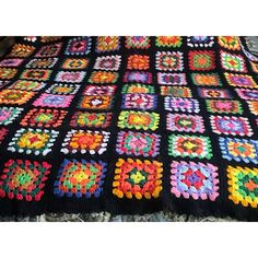 a crocheted blanket with multicolored squares on the top and bottom, sitting on a bed