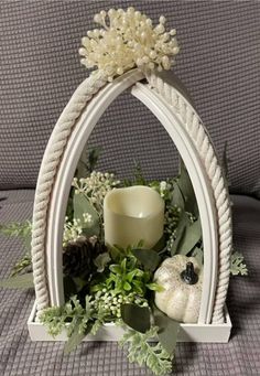 a white candle holder with greenery and flowers