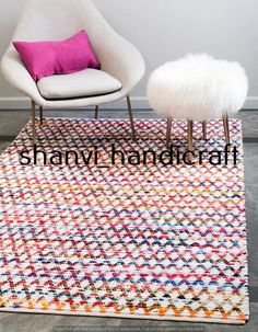 a white chair sitting on top of a wooden floor next to a pink and white rug