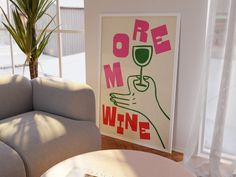 there is a poster on the wall next to a couch and table with a glass of wine in it