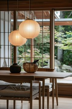 three lamps hanging over a table in a room with wood flooring and large windows