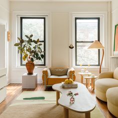 a living room filled with furniture and two large windows