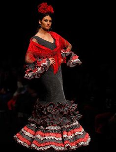 a woman is walking down the runway in a red and black dress