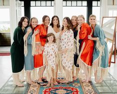 a group of women standing next to each other in front of a rug with fringes on it