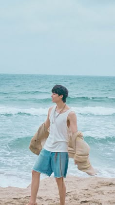 a man standing on top of a sandy beach next to the ocean