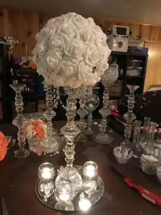 a table topped with lots of glass vases filled with white flowers and candle holders