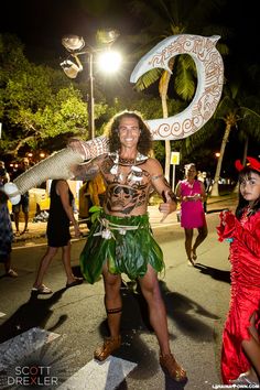 two people dressed in costumes are dancing on the street at night with palm trees behind them