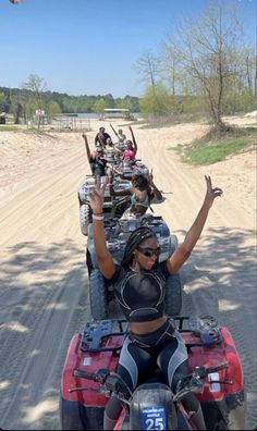 a group of people riding on the back of four wheelers down a dirt road