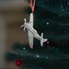 an ornament hanging from a christmas tree in the shape of a plane on it's side