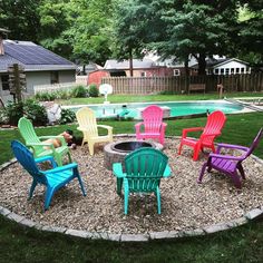 colorful lawn chairs sitting around a fire pit in the middle of a yard with an above ground swimming pool