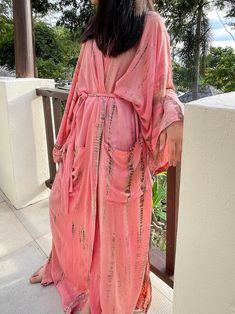 Lightweight and breathable with its gorgeous oversized length, the Swan - Peach Pink Kimono Robe is a must-have with its vibrant color. This relaxed design features a gorgeous tie-dye print paired with a chic waist tie. side pockets and elegant side slits. Layer it on over your favorite outfit for an effortless pop of color. Features: Lightweight feel Very comfortable and breathable Tie-dye Handmade Oversized fit Long sleeves Removable waist tie closure Two pockets Side slits at the hem Size + F Elegant Boho Outfit, Oversized Kimono, Tie Dye Kimono, Bridesmaid Kimono, Kaftan Designs, Pink Kimono, Mode Kimono, Boho Dresses Long, Kimono Robes