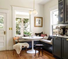 a white table and some chairs in a room with wood floors, windows and cabinets