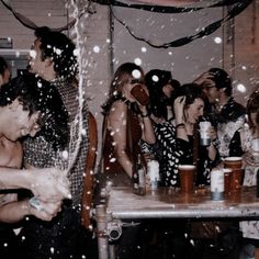 a group of people sitting around a table with drinks in front of them and confetti falling from the ceiling