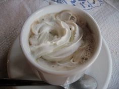 a cup filled with whipped cream on top of a white plate