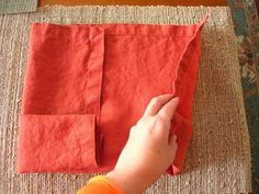 someone is cutting fabric with scissors on a table cloth that has been folded into two rectangles