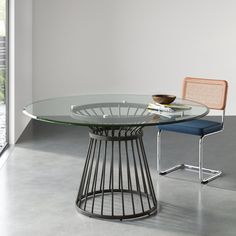 a glass table with two chairs and a bowl on the top, in front of a window