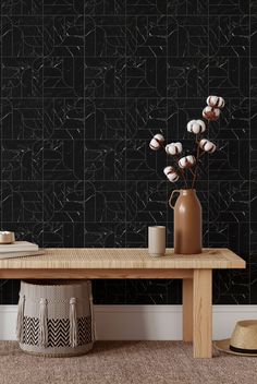 a wooden table topped with a vase filled with white flowers next to a black wall