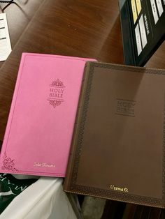 two pink and brown binders sitting on top of a wooden table