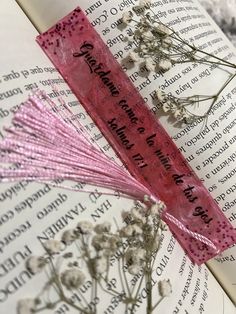 an open book with pink ribbon and flowers on it's cover, next to a candle