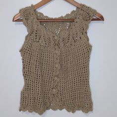 a crocheted top hanging on a wooden hanger