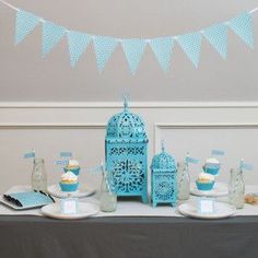 a table topped with cupcakes and cake next to a blue birdcage