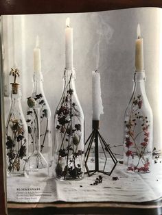 an open book with candles and flowers in glass bottles on the table next to each other