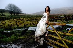 a woman standing on top of a wooden fence