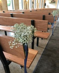 a bouquet of flowers sitting on top of a wooden bench in a room filled with pews