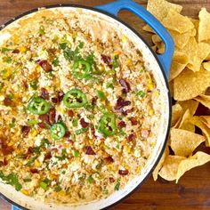 a blue pot filled with mexican food next to tortilla chips on top of a wooden table