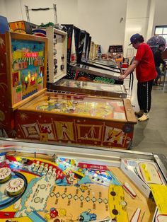 two people looking at an old fashioned pinball machine