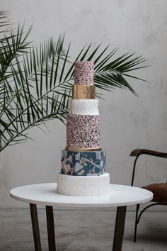 a multi layer cake sitting on top of a white table next to a palm tree