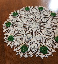 a crocheted doily with shamrocks on it sitting on a wooden table