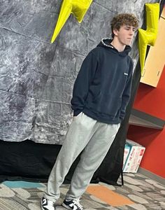 a young man is standing in front of a wall with yellow lightning signs on it