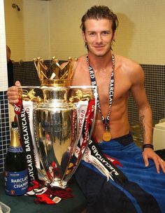 a shirtless man sitting on a bench holding a trophy