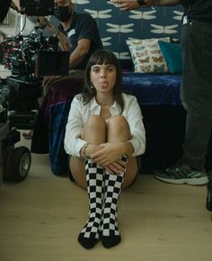 a woman is sitting on the floor with her legs crossed and wearing checkered socks