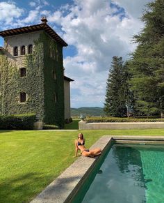 a woman sitting on the edge of a pool next to a building