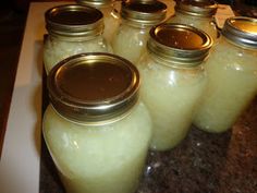 several jars with lids are lined up on a counter top, one is filled with liquid